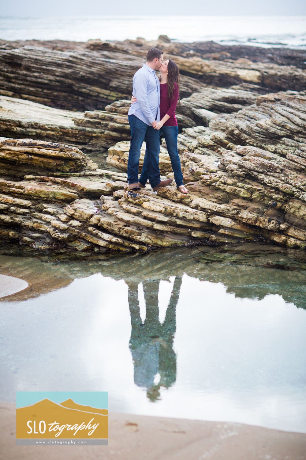 couple kissing on reef with reflection in tide pool