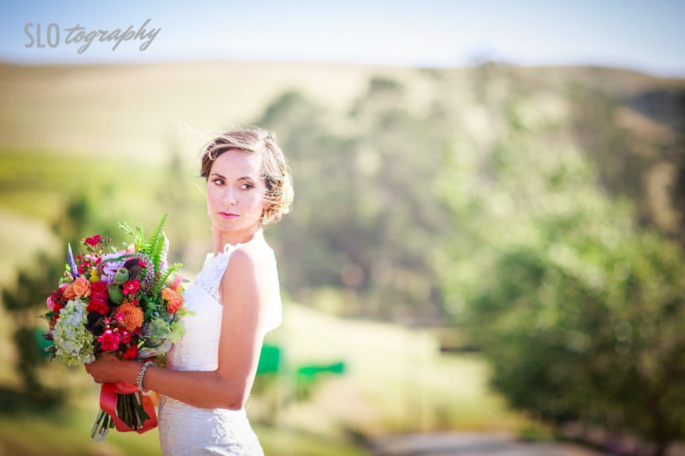 Bride Looks Over Shoulder with Greenery Background
